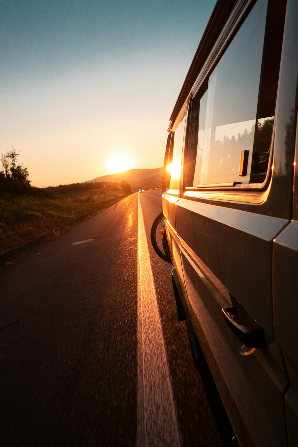 gray vehicle parked on road near tree during golden hour