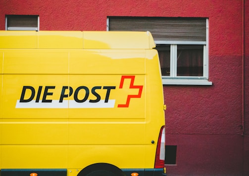 yellow Die Post+ van park beside road