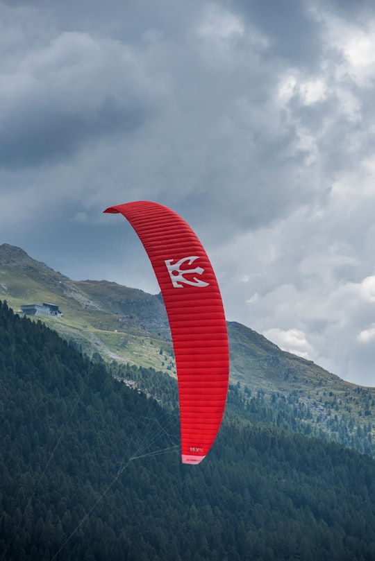 person riding red parachute at daytime in Lake Silvaplana Switzerland
