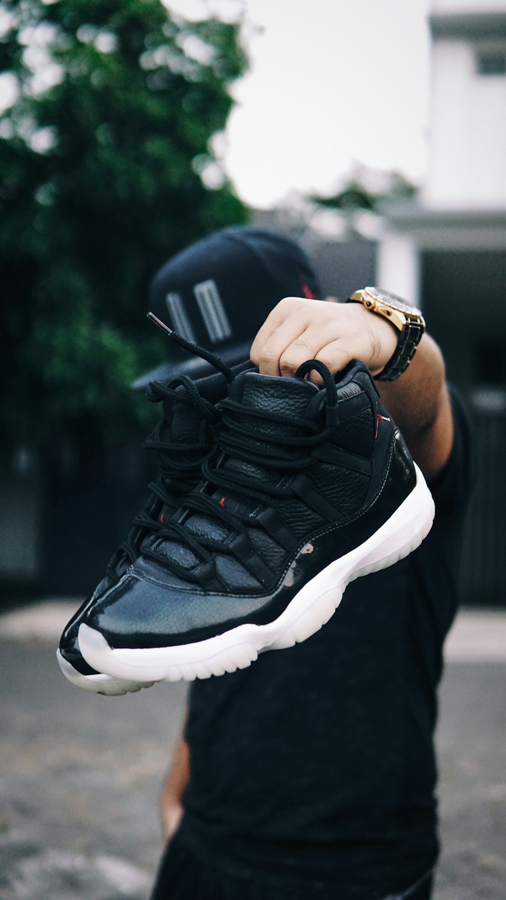 person holding pair of black-and-white Air Jordan 11's