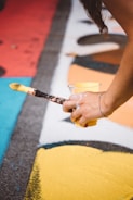 person holding cup with yellow paint and paintbrush
