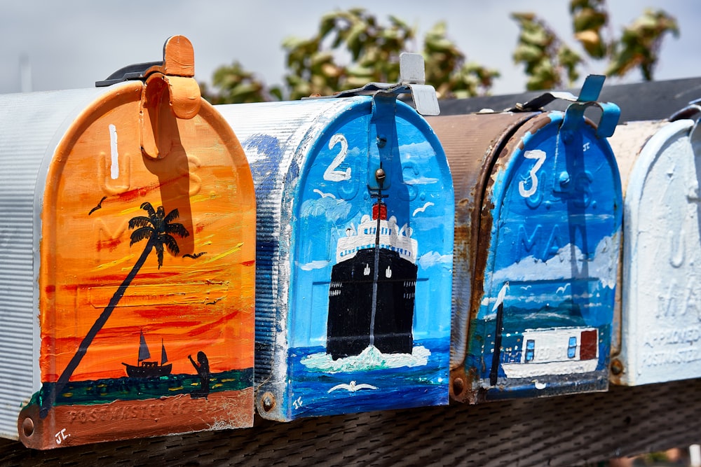 four assorted-color mailboxes on black surface