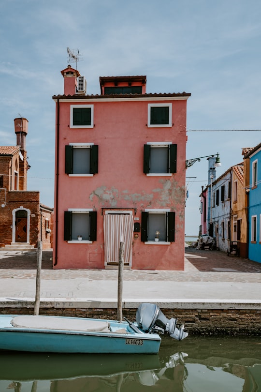 blue boat on body of water near pink house in Burano Italy