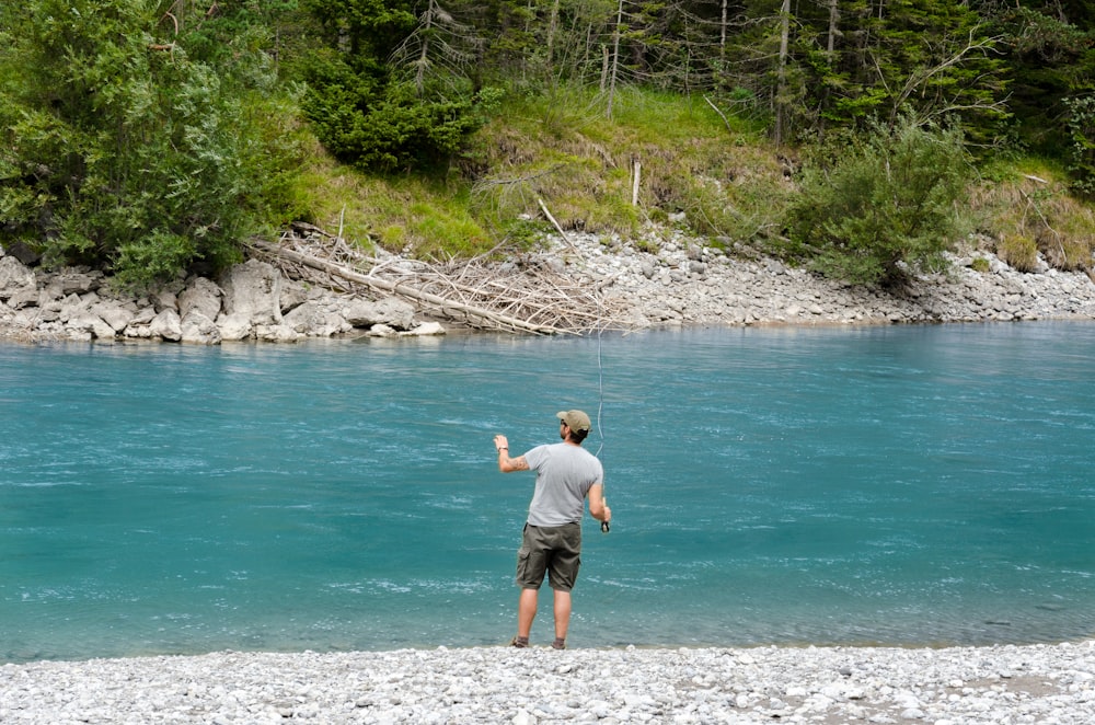 man holding fishing rod in front of body of water