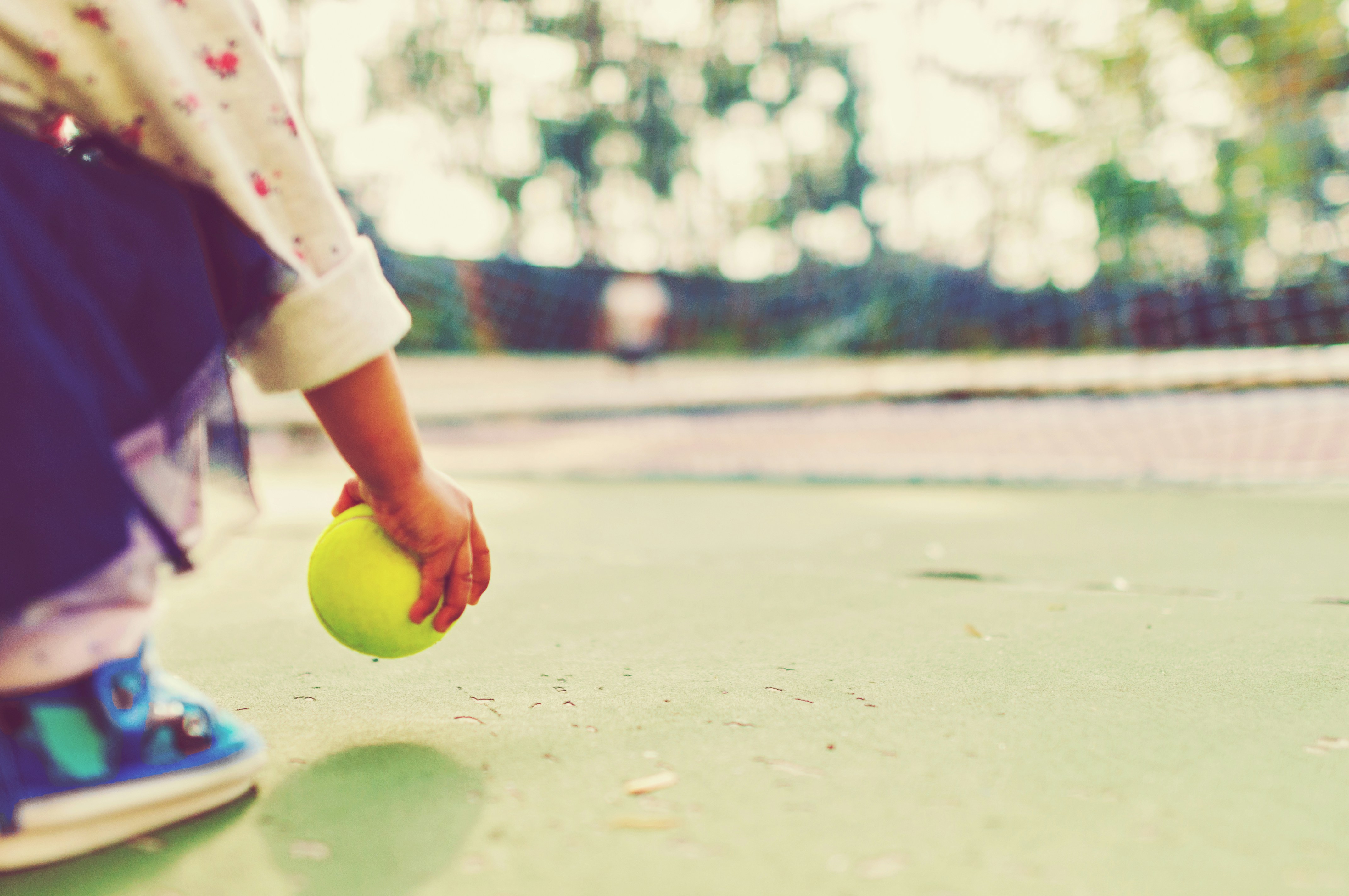 A toddler holding a tennis ball in a play ground