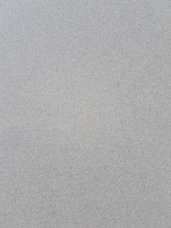 A textured surface with a gritty appearance, consisting of fine grains evenly distributed in a uniform pattern.