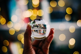 person holding clear crystal ball with bokeh background photography