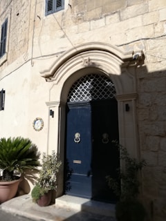 Elegant charcoal gray iron door standing proudly framed by warm-toned stone, inviting visitors inside.