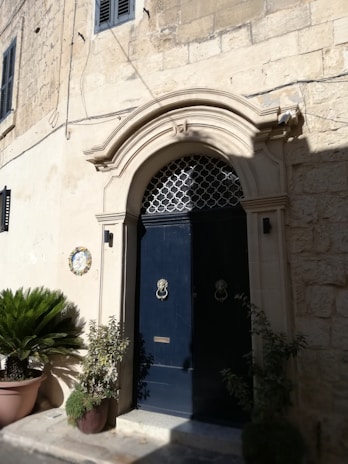 Elegant charcoal gray iron door standing proudly framed by warm-toned stone, inviting visitors inside.