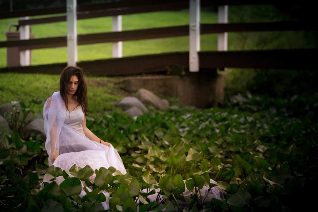 woman in white dress sitting beside plants