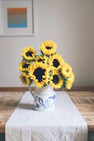 A bright yellow ceramic pitcher filled with fresh wildflowers on a wooden table.