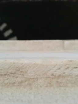 A blurred image with a dark background and a light-colored foreground displaying a grainy texture. There are indistinct white shapes on the left side.