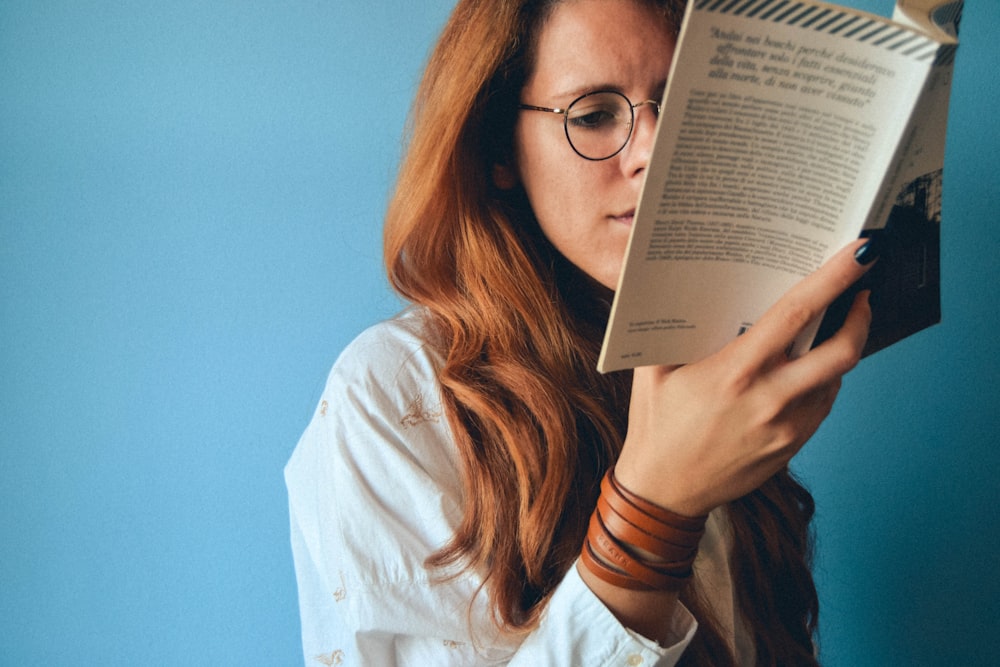 Frau mit Brille hält ein Buch in der Hand