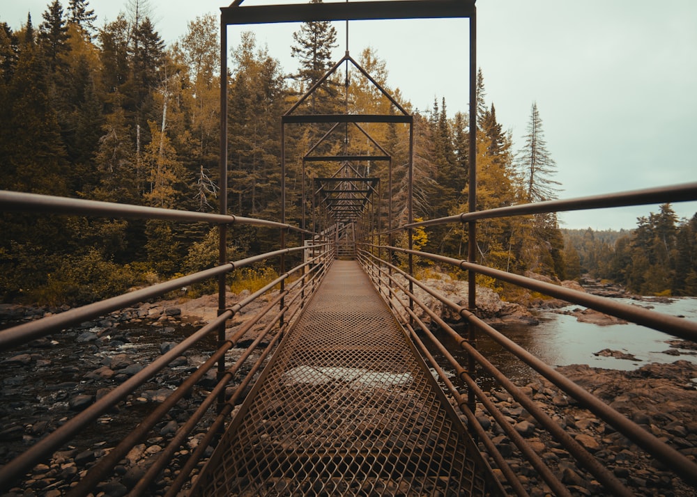 Puente de metal marrón sobre el río rocoso Fotografía arquitectónica durante el día