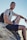 smiling man sitting on gray rock at daytime
