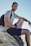 smiling man sitting on gray rock at daytime