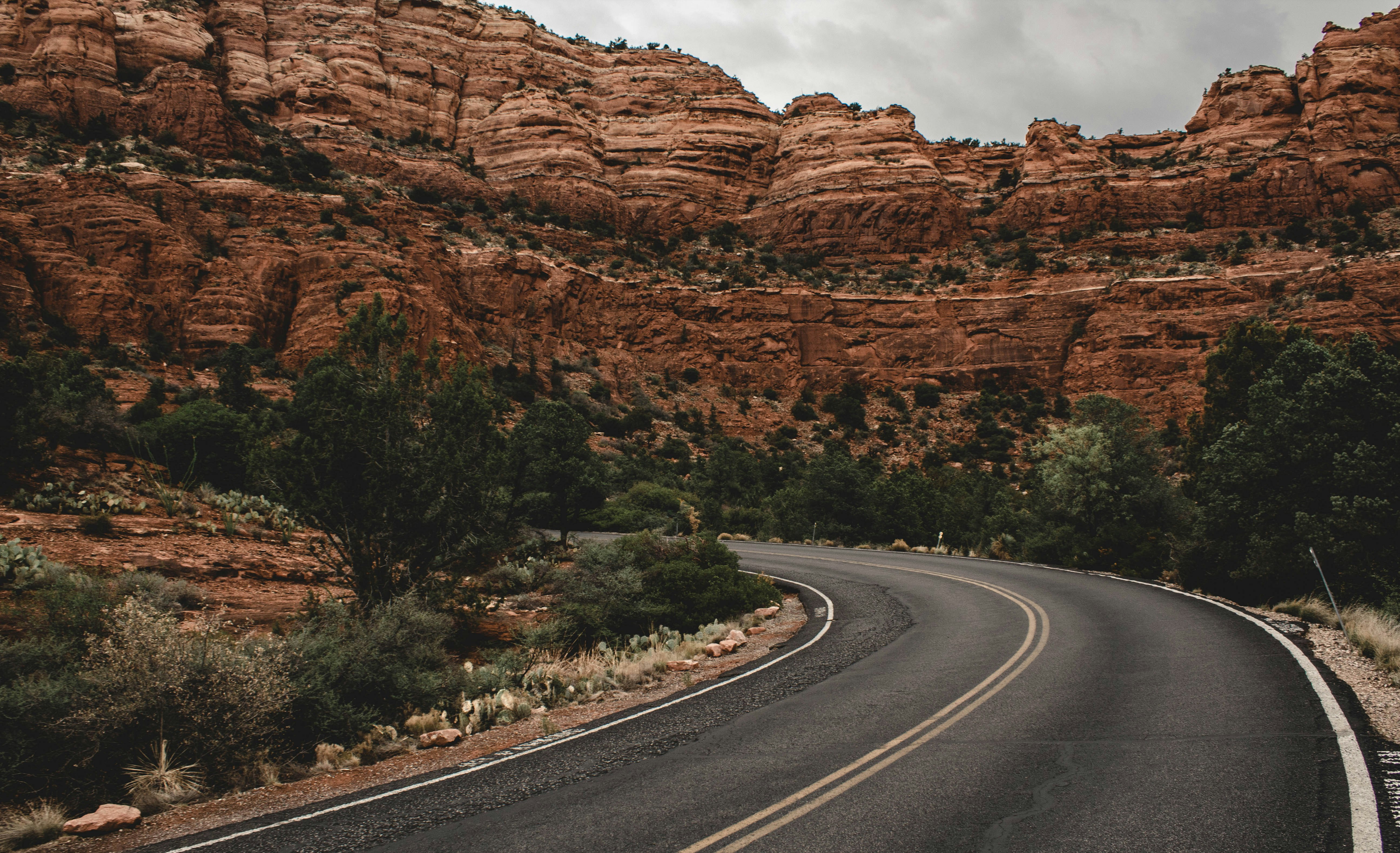 clear road in between hill under gray clouds