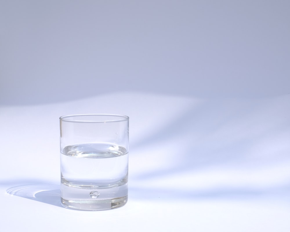 Short stem wine glass half full of water on a white background with a  reflection Stock Photo