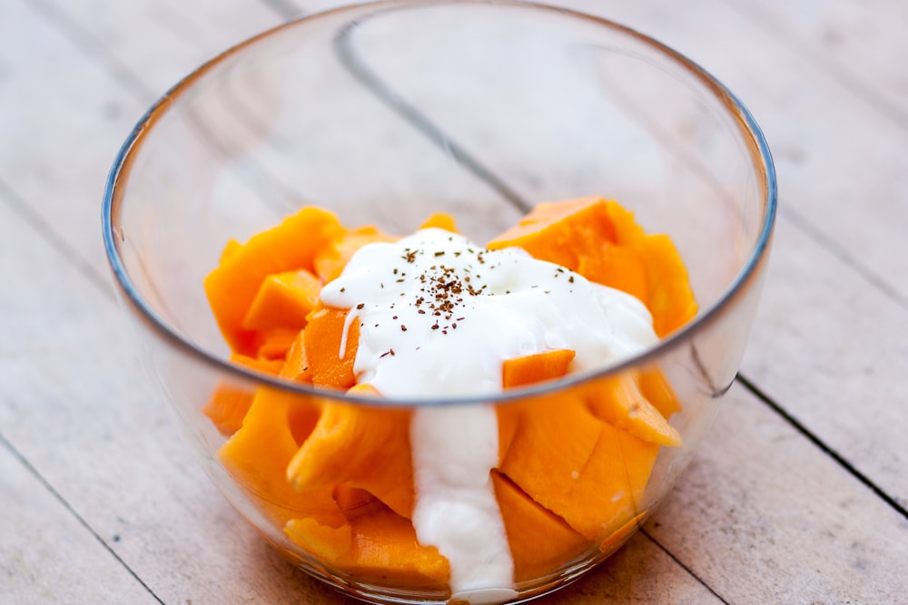 sliced of papaya fruit with white cream on clear glass bowl