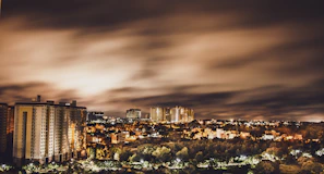 A cinematic shot of a cityscape at night with glowing lights and a dramatic sky, evoking storytelling.