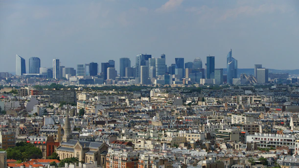 A panoramic view of a bustling European financial district with modern skyscrapers and historic buildings under a clear sky.