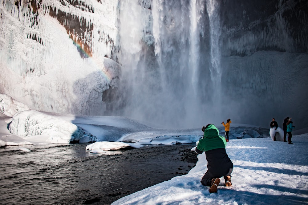 person kneeling beside body of water