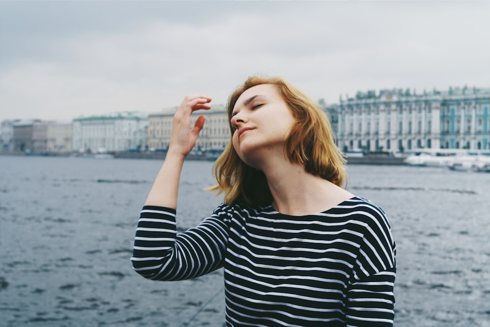 woman raising her right hand near body of water