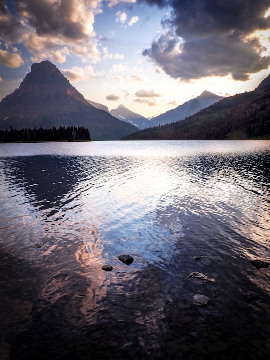 landscape photo of body of water surrounded by mountains in Glacier National Park, Two Medicine Lake with Sinopah Mountain United States