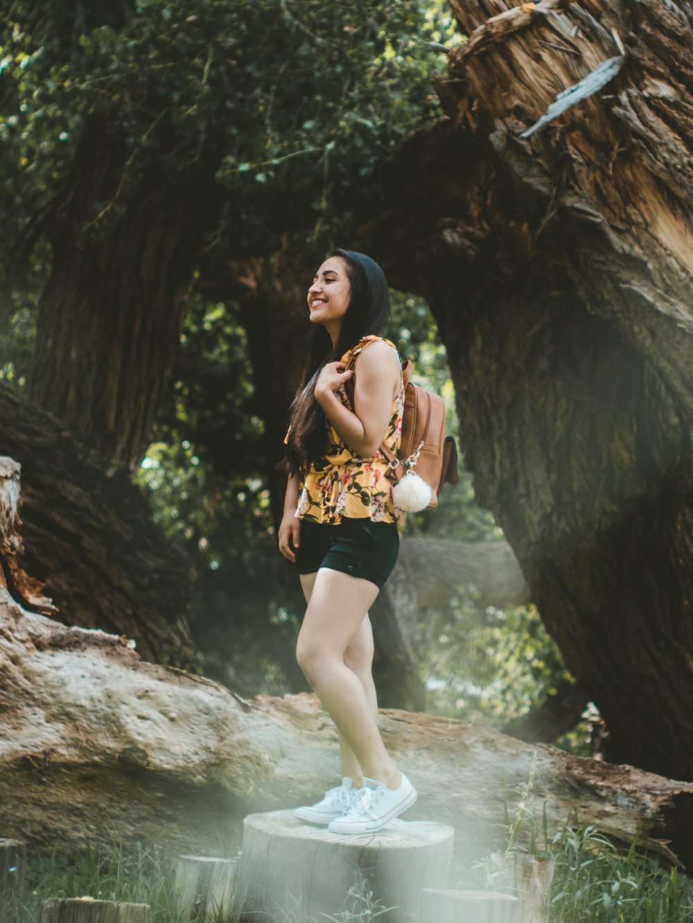 woman standing on tree trunk beside tree