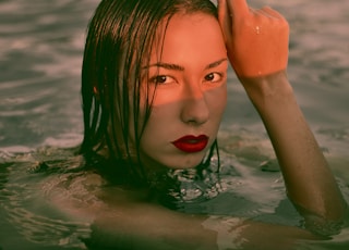 woman wearing red lipstick on body of water