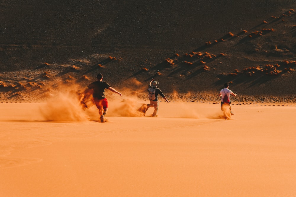 Tres hombres corriendo en el desierto durante el día