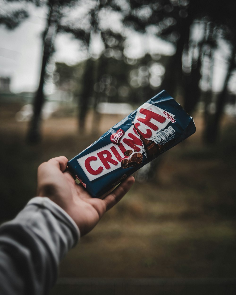 personne tenant une barre de chocolat Nestlé Crunch