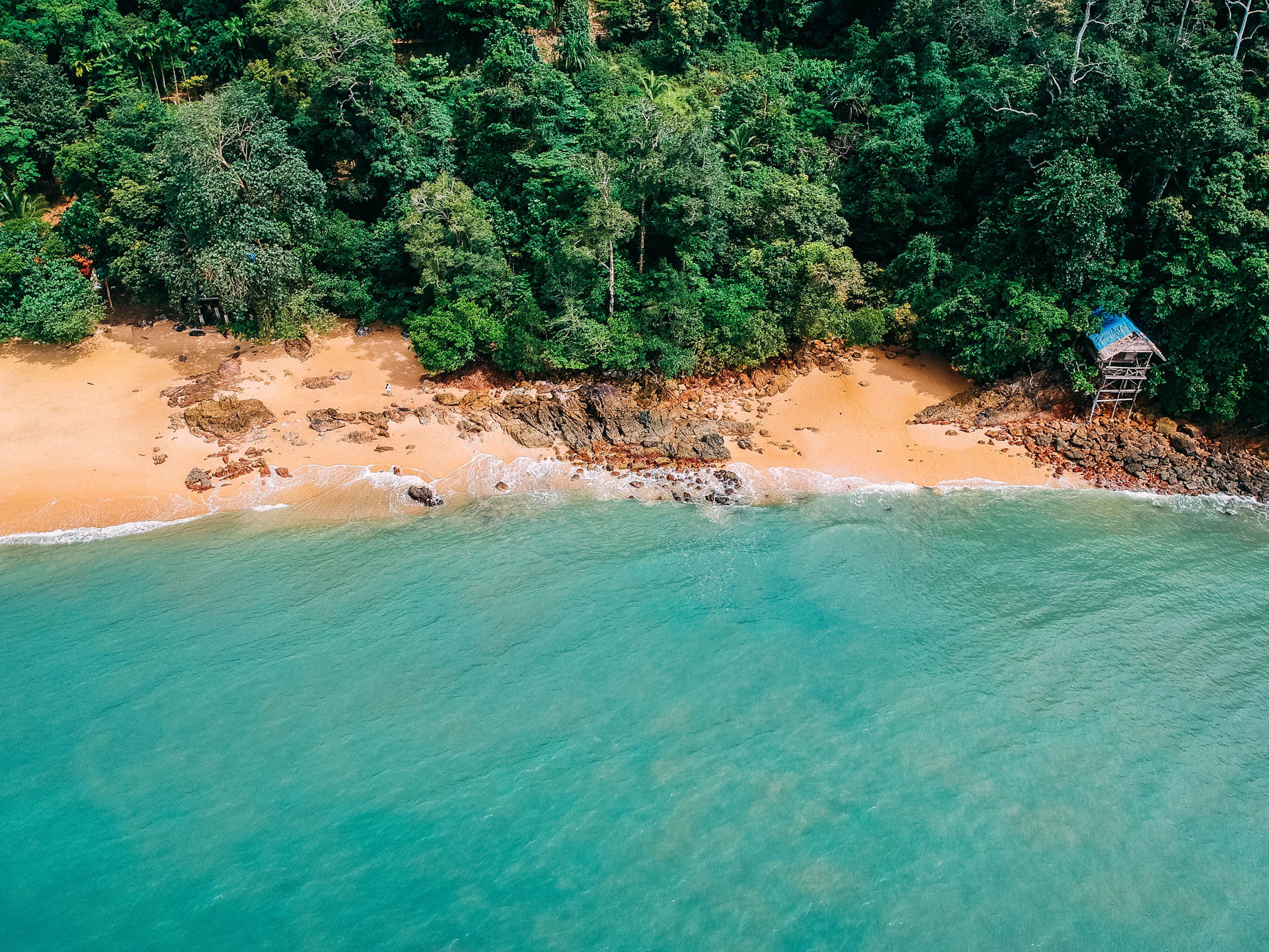 A breathtaking aerial view of a secluded luxury beach resort in Brazil at sunset, with golden sands and crystal-clear waters.