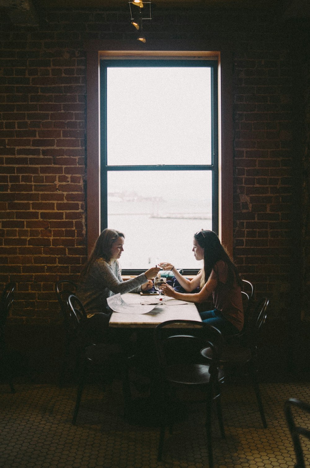 woman sitting in front of woman near window