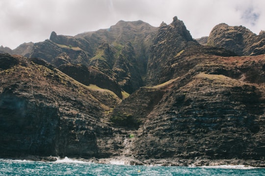 rock mountains near waterfalls under gray sky in Kauai United States