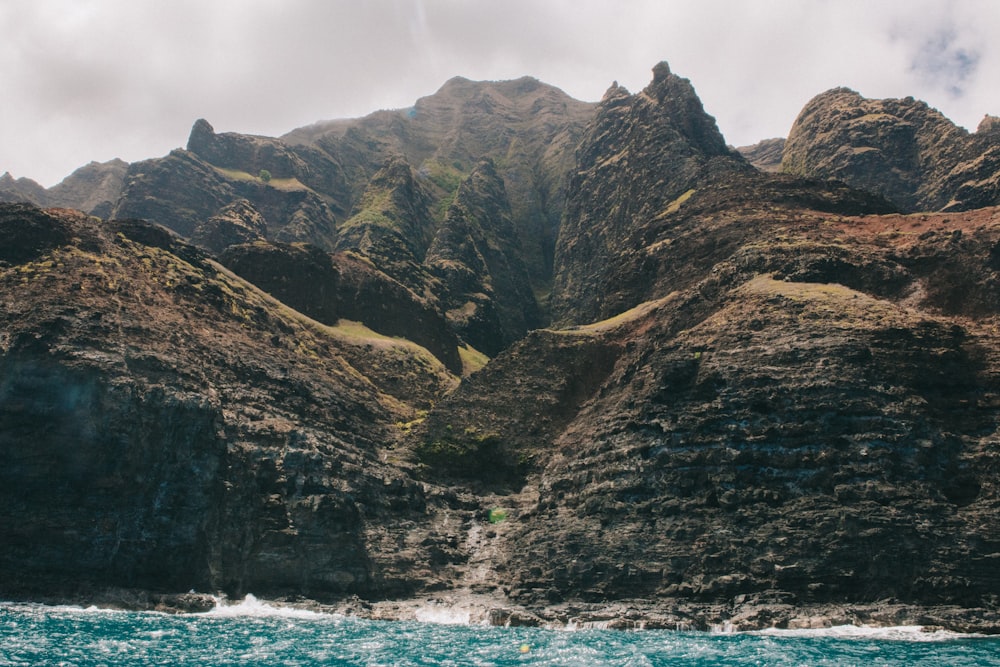 rock mountains near waterfalls under gray sky