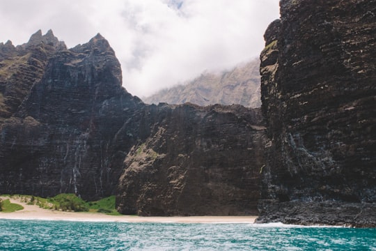 cliff beside body of water in Nā Pali Coast State Wilderness Park United States