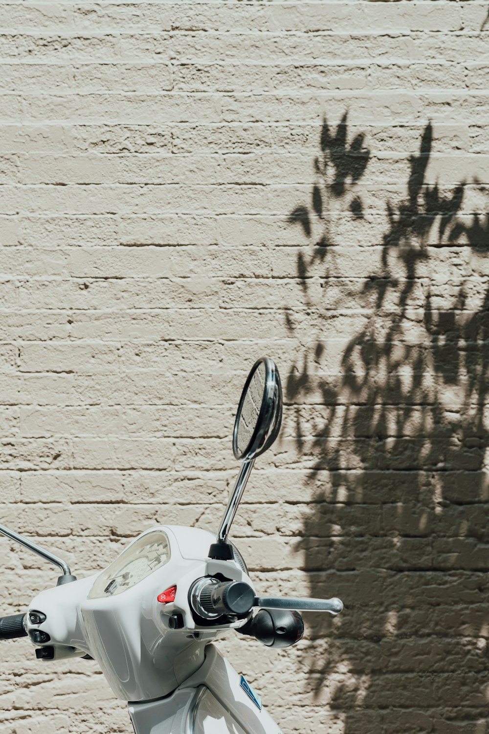 motocicletta bianca accanto al muro bianco durante il giorno