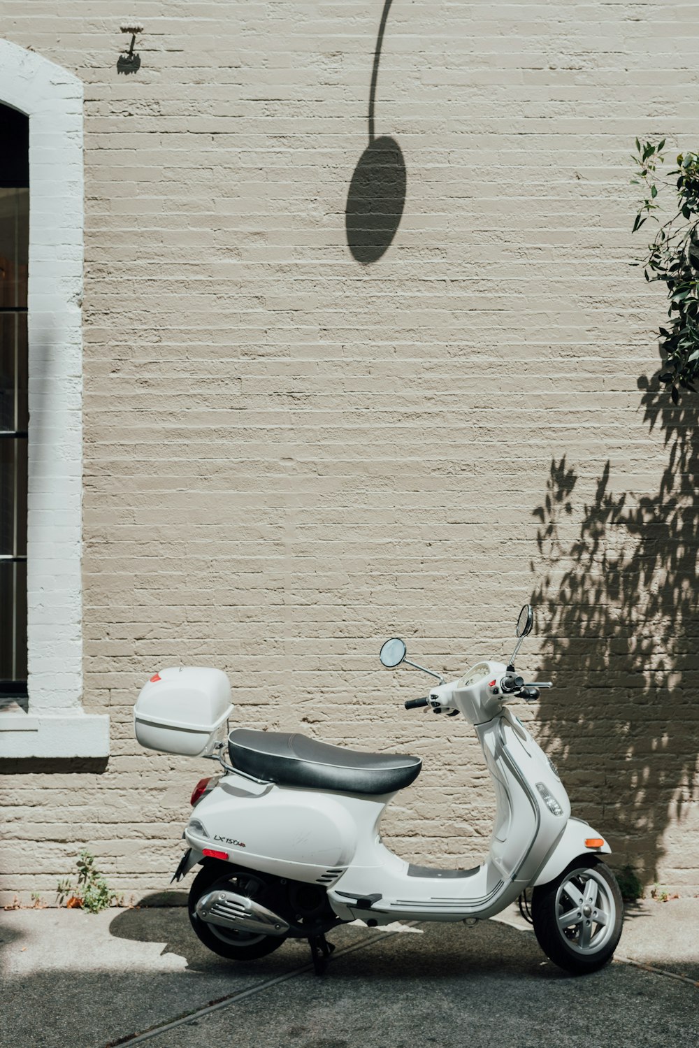 white and black motor scooter beside white wall