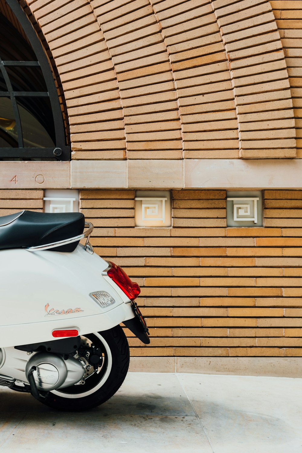 Motocicleta branca estacionada ao lado de parede marrom