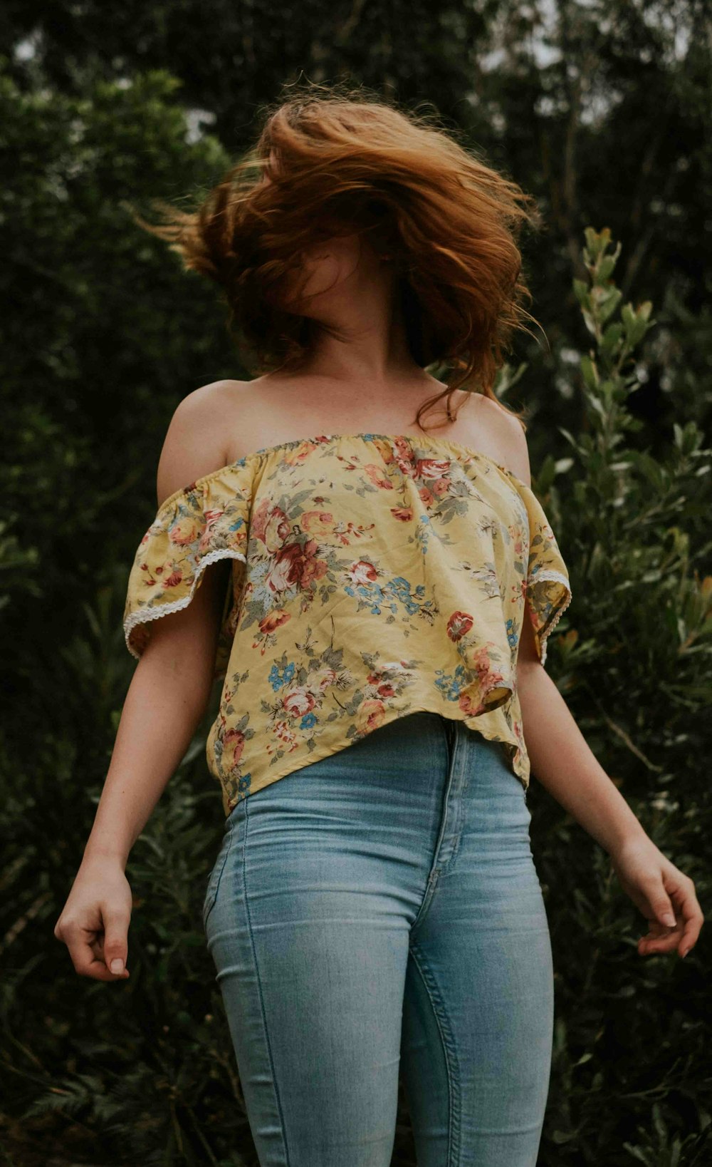 woman wearing blue jeans standing behind plants