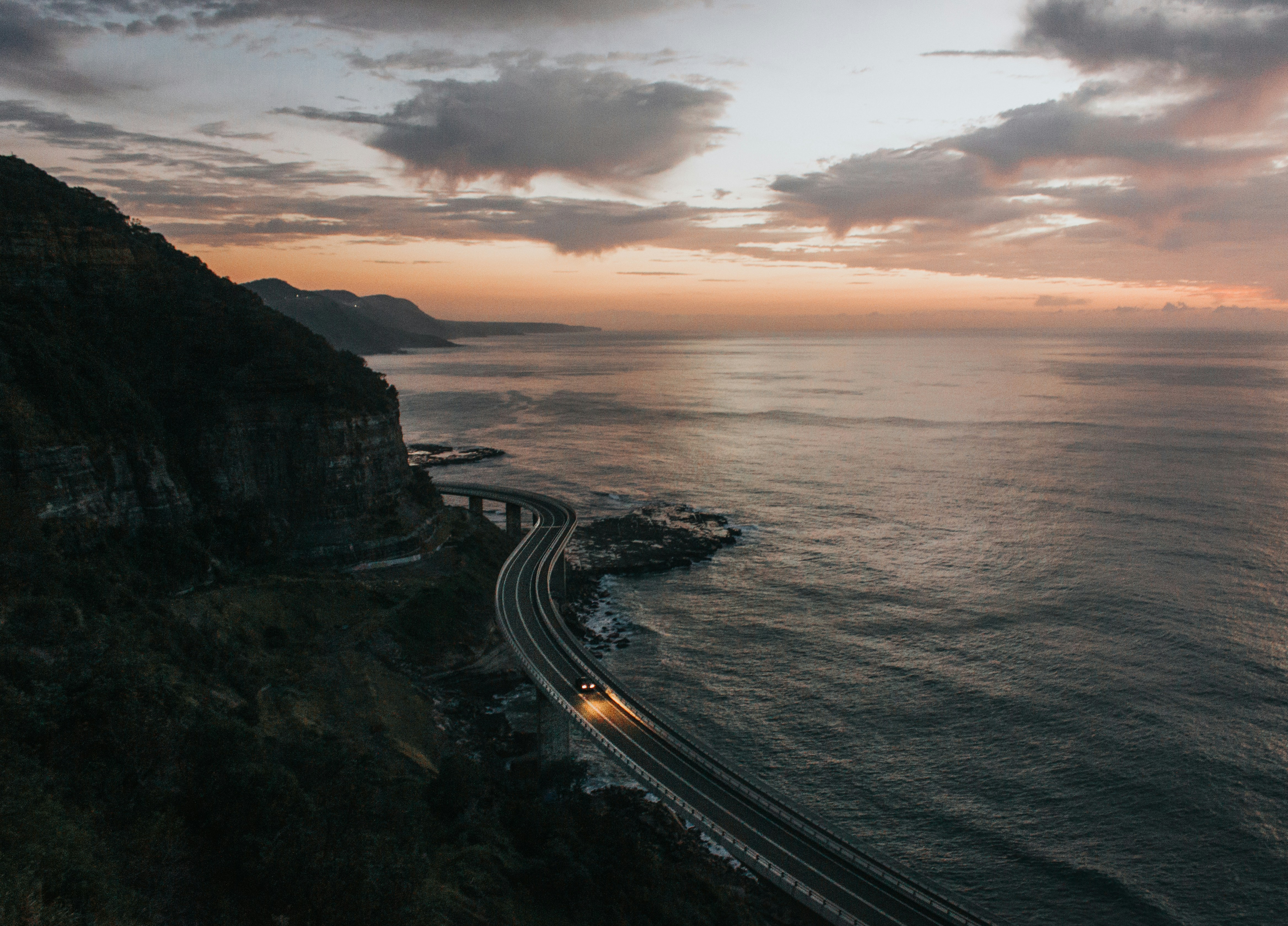 road beside body of water, Sea Cliff Bridge - Drives at Dawn