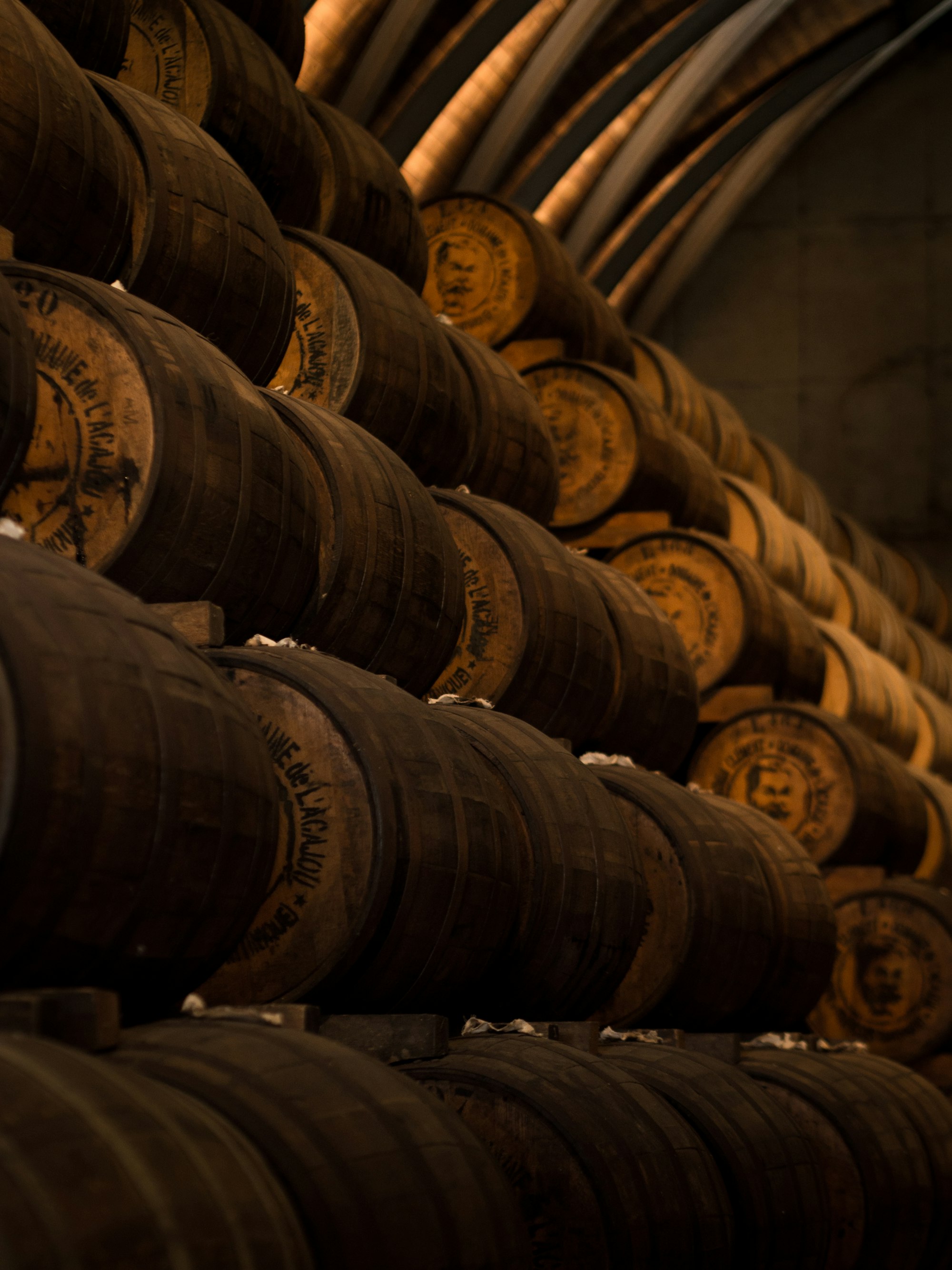 Barrels of aging spirits stacked against a wall.