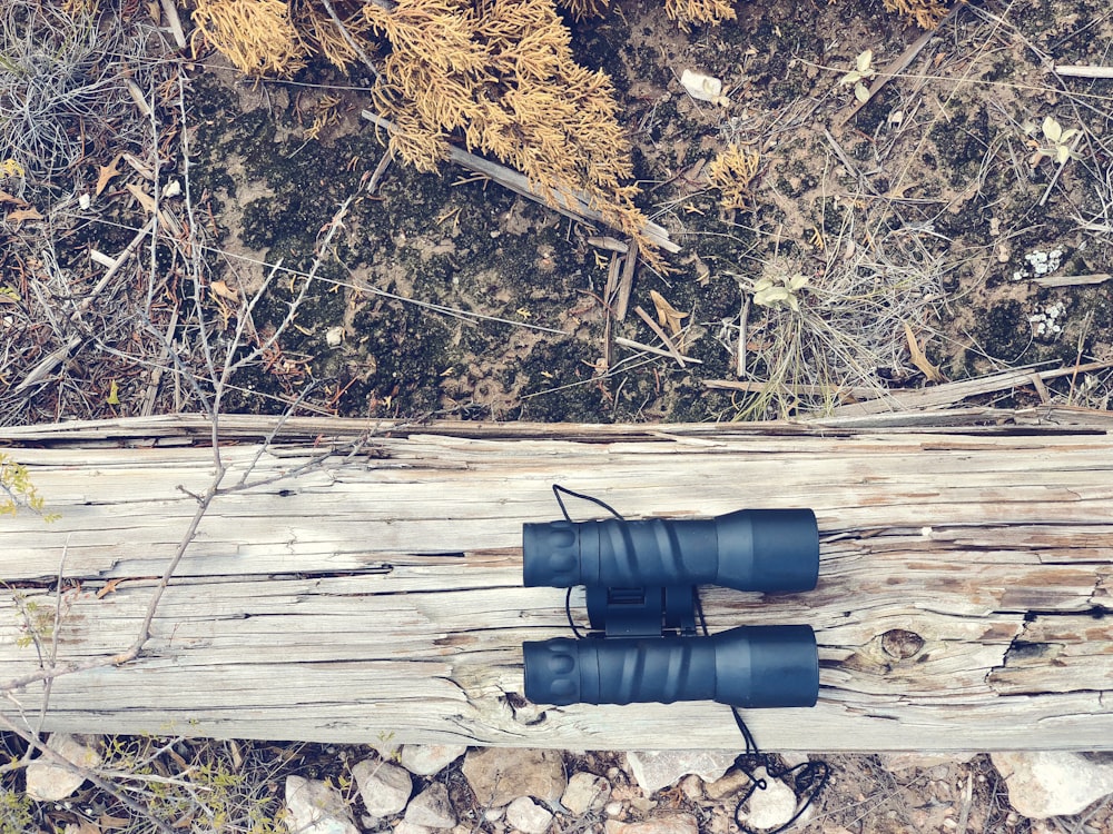 black binoculars on brown wood log