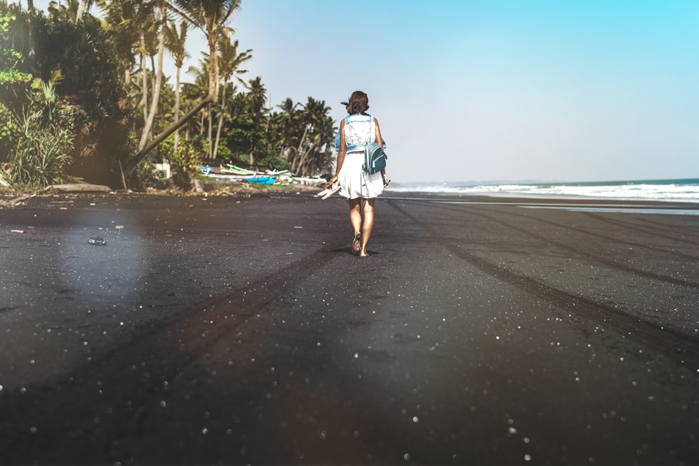 donna che cammina in riva al mare vicino alle palme