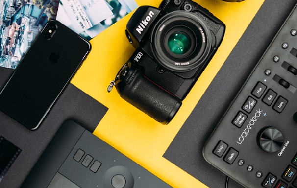 black Nikon DSLR camera beside space gray iPhone X