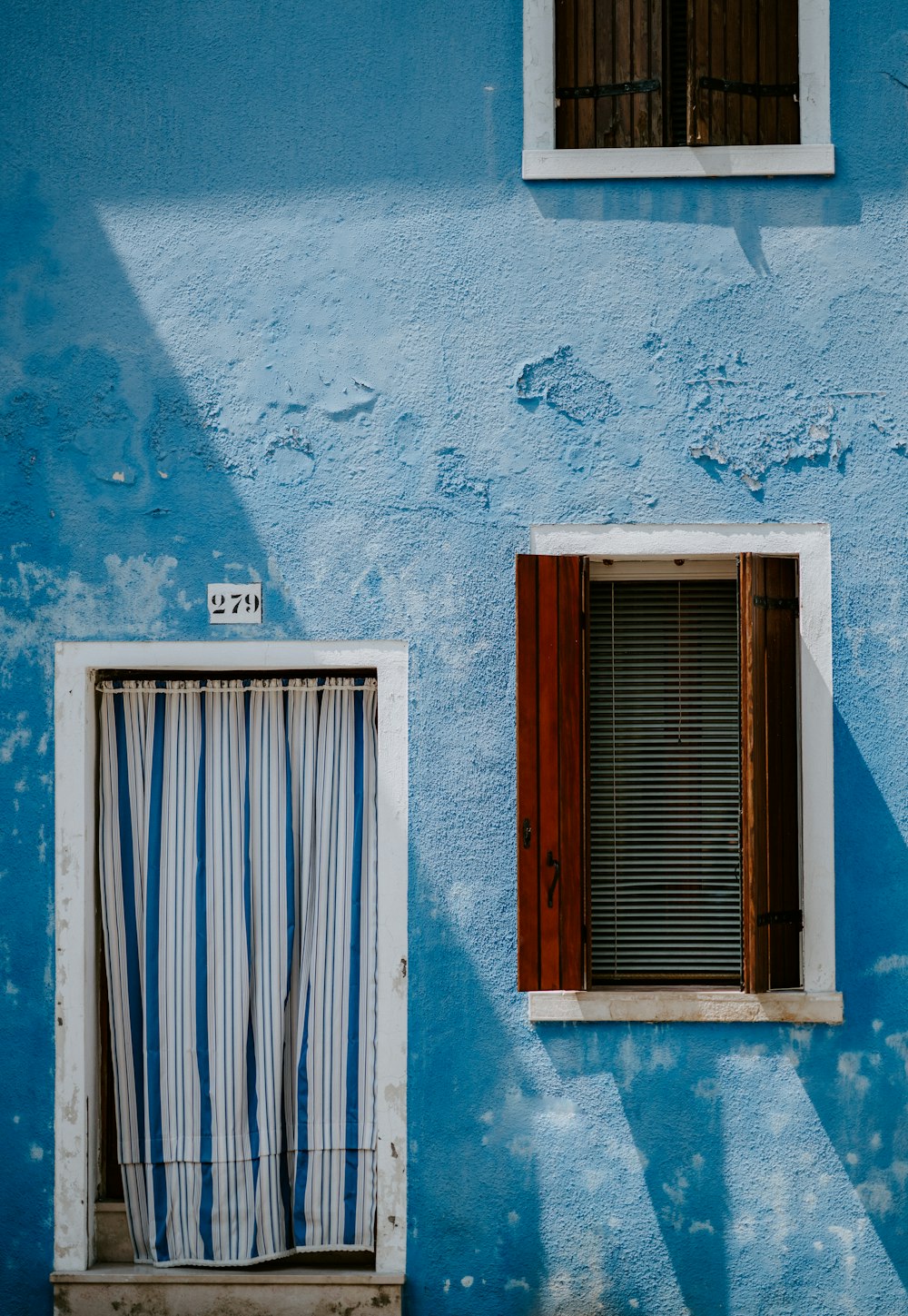 Casa azul con cortina en puerta y ventana de madera