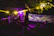 A lively outdoor garden party with colorful lights and a DJ booth in the background.