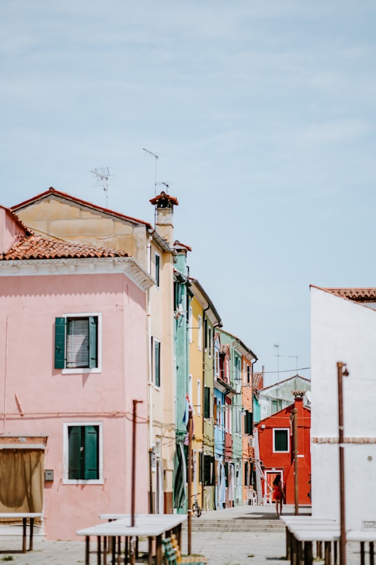 person walking on sidewalk near houses taken during daytime in Burano Italy