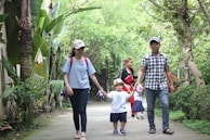 A nanny and kids hiking on a trail surrounded by vibrant tropical plants.